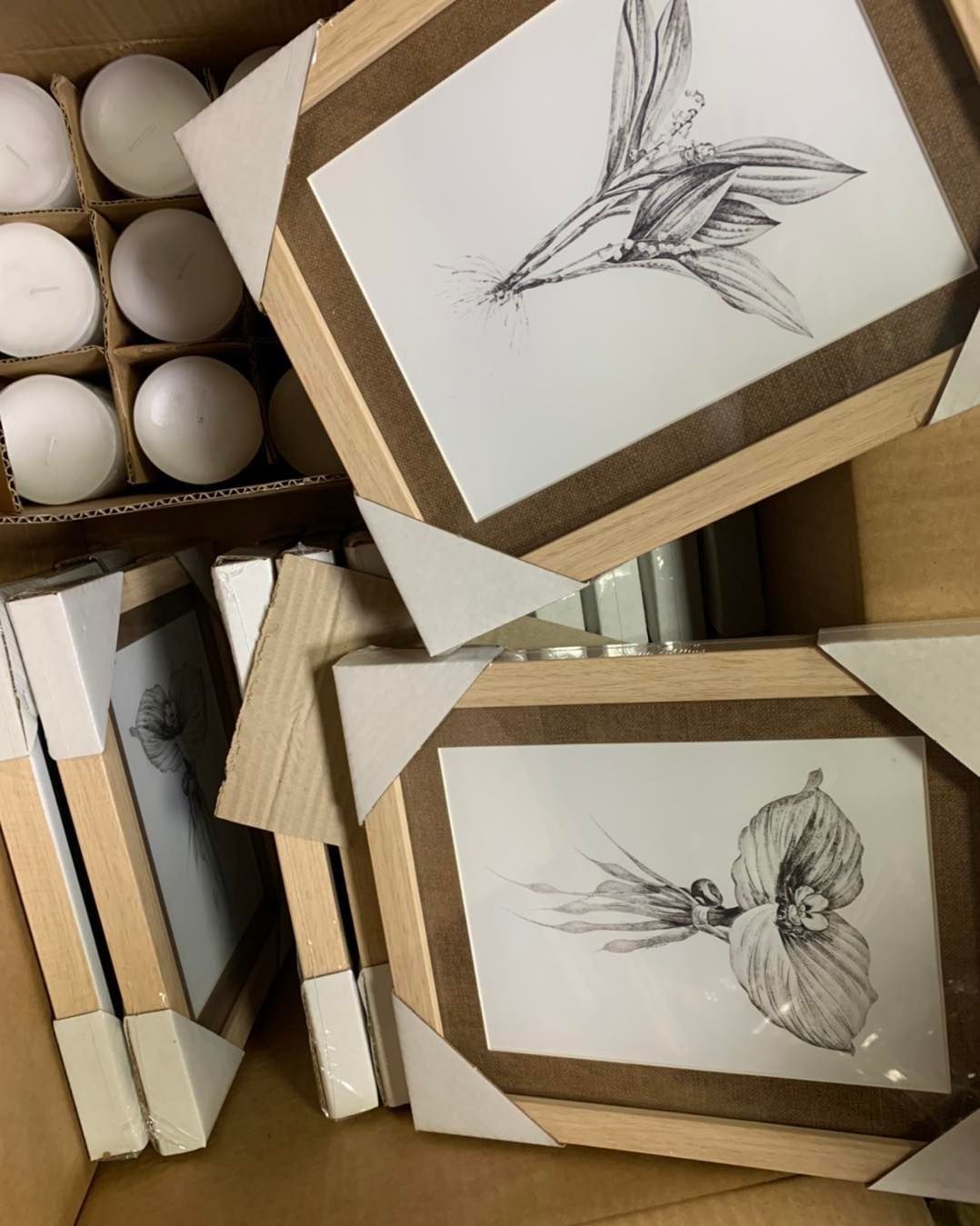 Caja con láminas florales enmarcadas y velas.