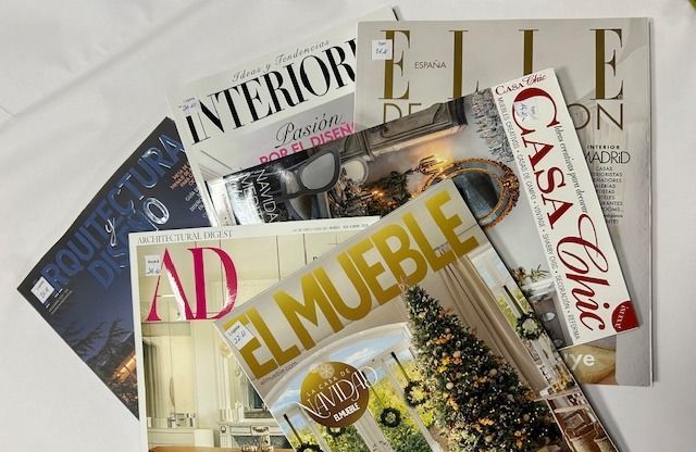 Pila de revistas de diseño de interiores: AD, El Mueble, Elle Décor, Casa Chic y más sobre una superficie blanca.