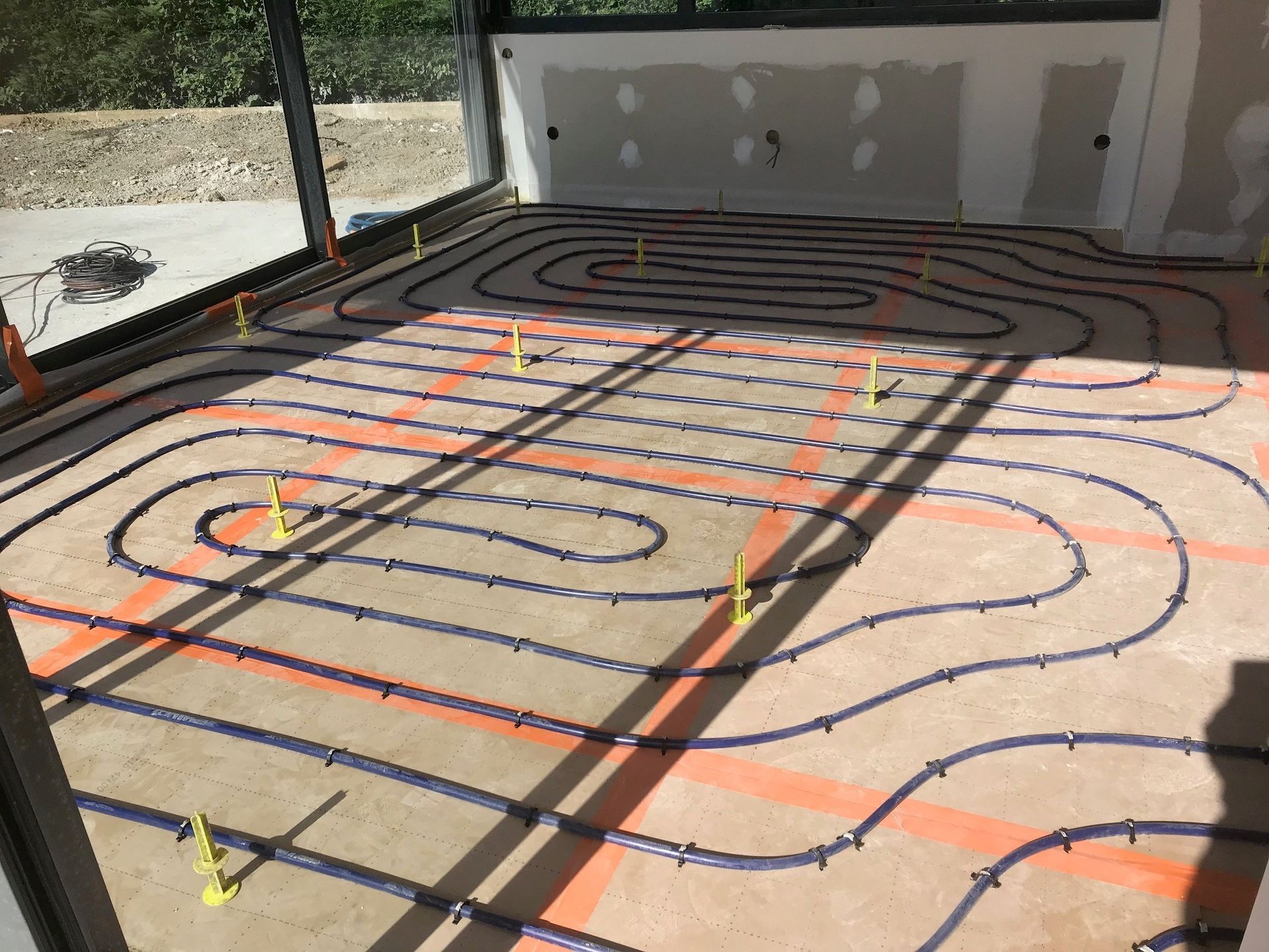 Des tuyaux de chauffage au sol rayonnant ont été disposés en serpentin sur un sol intérieur en béton lors de la construction.