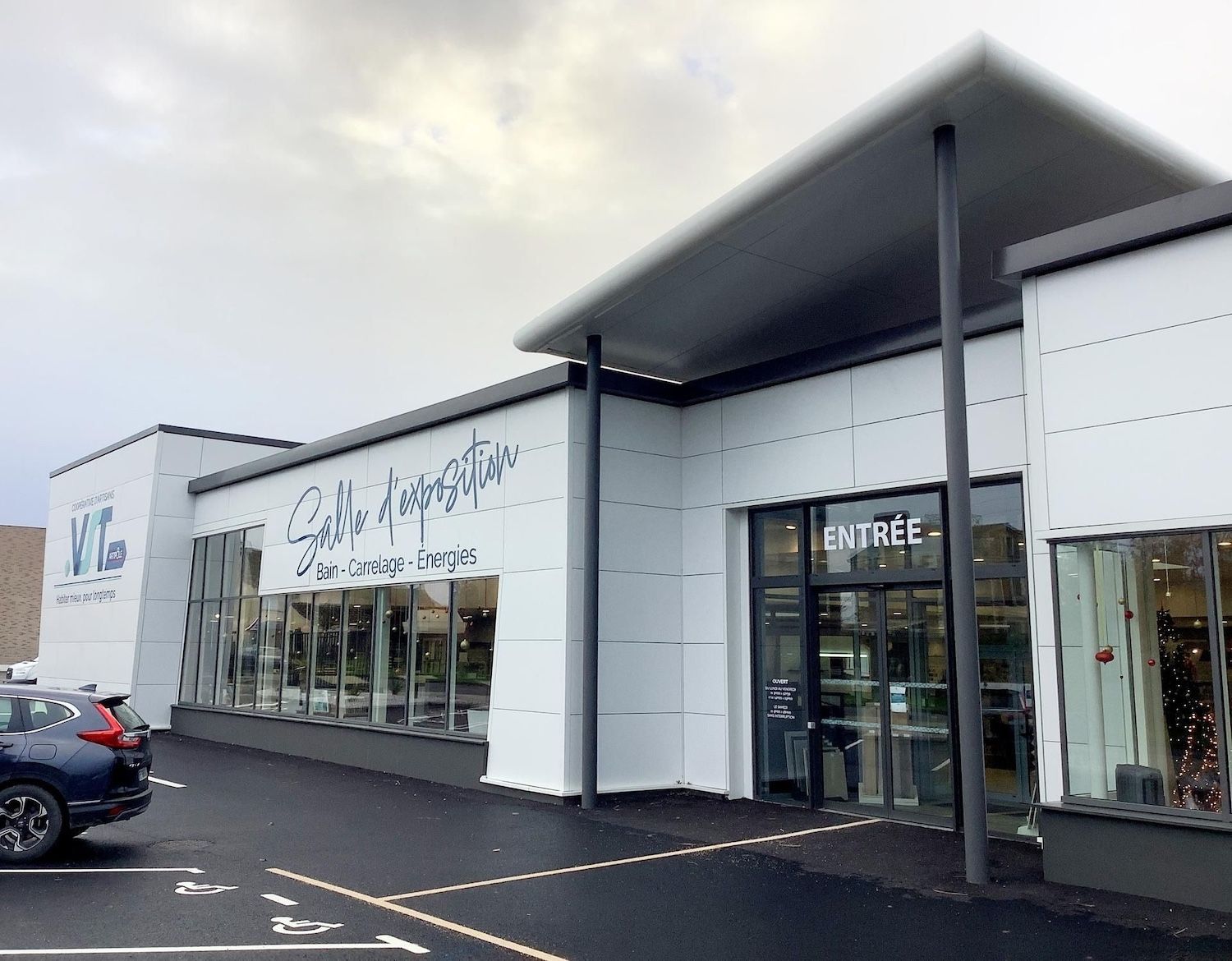 Bâtiment blanc moderne avec une enseigne « Salle d'inspiration », une entrée vitrée et un parking sombre devant.