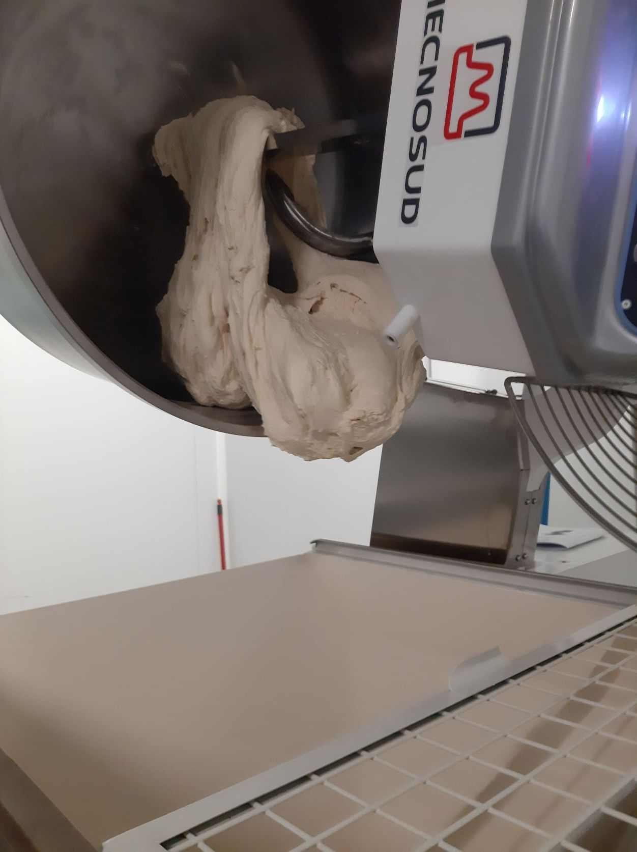 Pétrissage de pâte dans un pétrin à spirale Mecnosud, un gros appareil dans une cuisine.