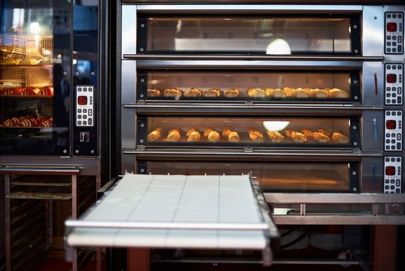 Four professionnel à trois niveaux pour la cuisson des pâtisseries. Une vitrine latérale avec des viennoiseries se trouve à côté du four.