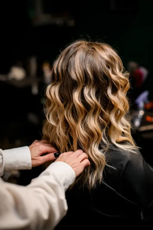 Cabello ondulado y con reflejos de una persona, peinado con las manos de alguien.