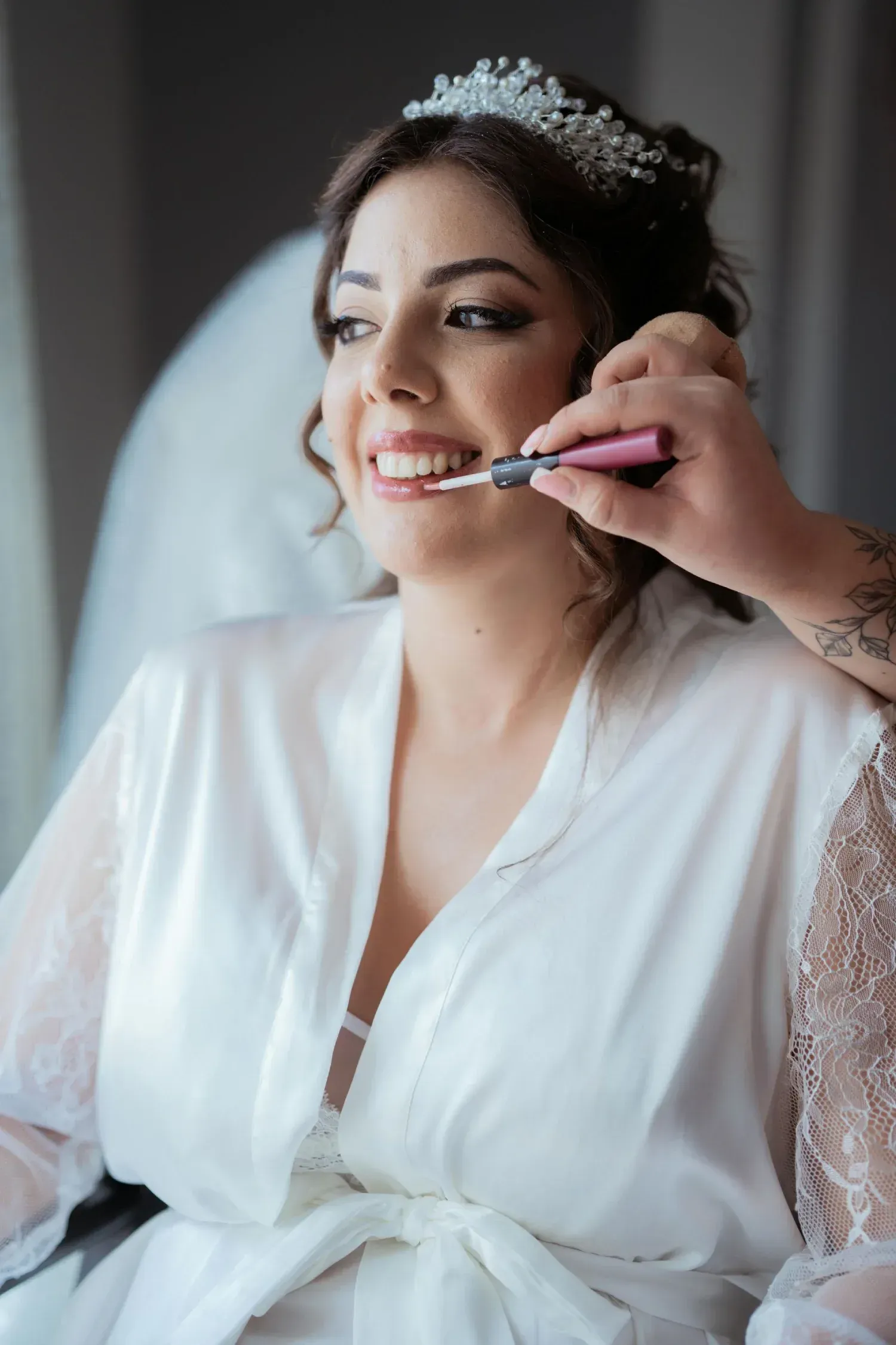Novia con lápiz labial aplicado, vestida con una túnica blanca y una tiara.