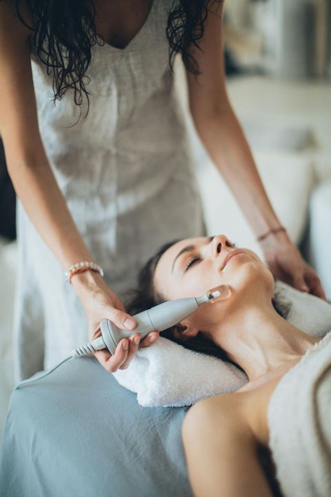 Mujer recibiendo un tratamiento facial. La esteticista le coloca el dispositivo en el rostro en un spa.