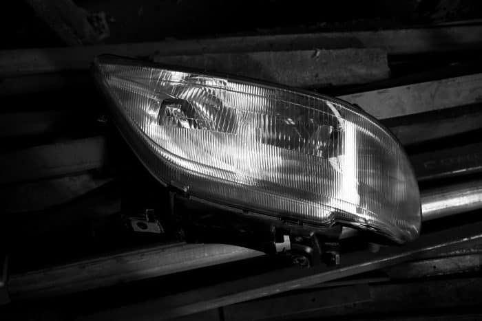 Gros plan d’un phare de voiture posé sur des lattes métalliques dans un environnement sombre