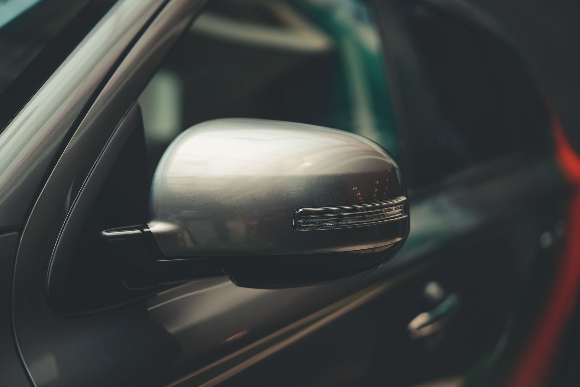 Gros plan sur le rétroviseur latéral argenté d’une voiture, dans un habitacle sombre