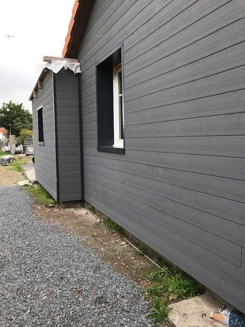 Bardage foncé sur une façade avec petite fenêtre blanche 