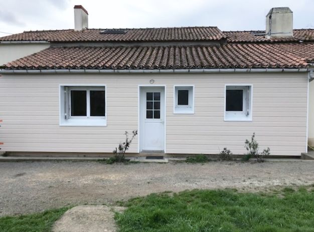 Bardage blanc sur petite maison avec les portes et fenêtres blanches 