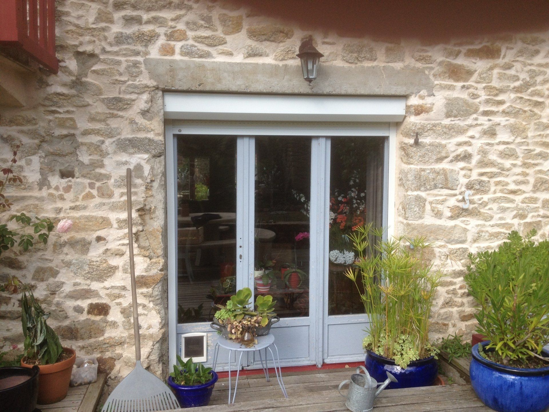 Porte-fenêtre blanche sur une façade en pierres anciennes