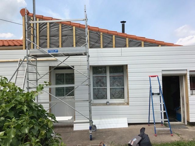 Bardage blanc en cours de réalisation sur une petite maison avec un toit en tuile