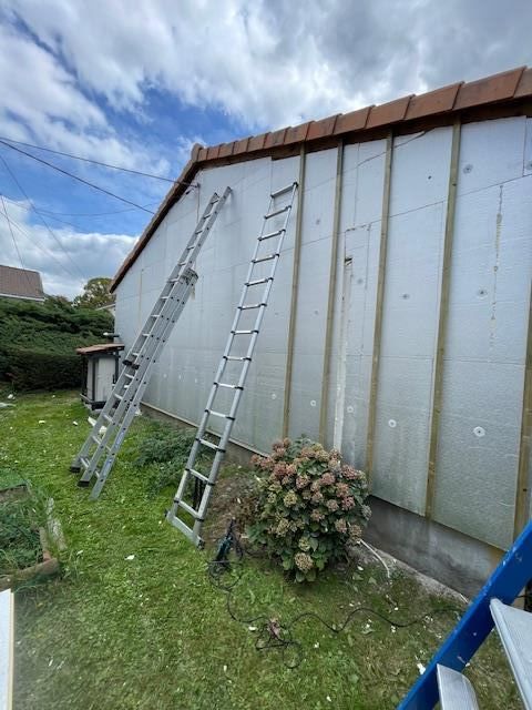 Pose de l'isolant thermique préalable à celle du bardage sur un chantier