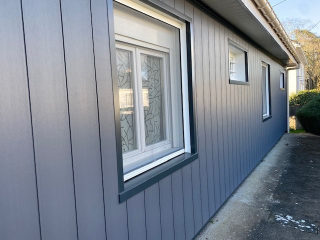 Bardage bleu foncé sur une façade avec fenêtres blanches