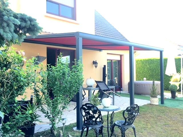 Pergola noire devant une façade crème 