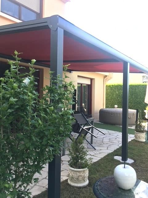 Pergola noire avec store rouge dans un beau jardin 