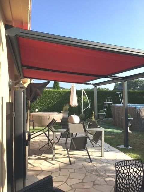 Belle pergola avec store rouge dans un jardin avec piscine