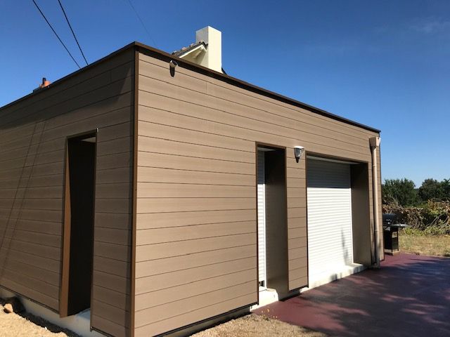 Bardage marron sur petite maison carrée avec porte de garage blanche