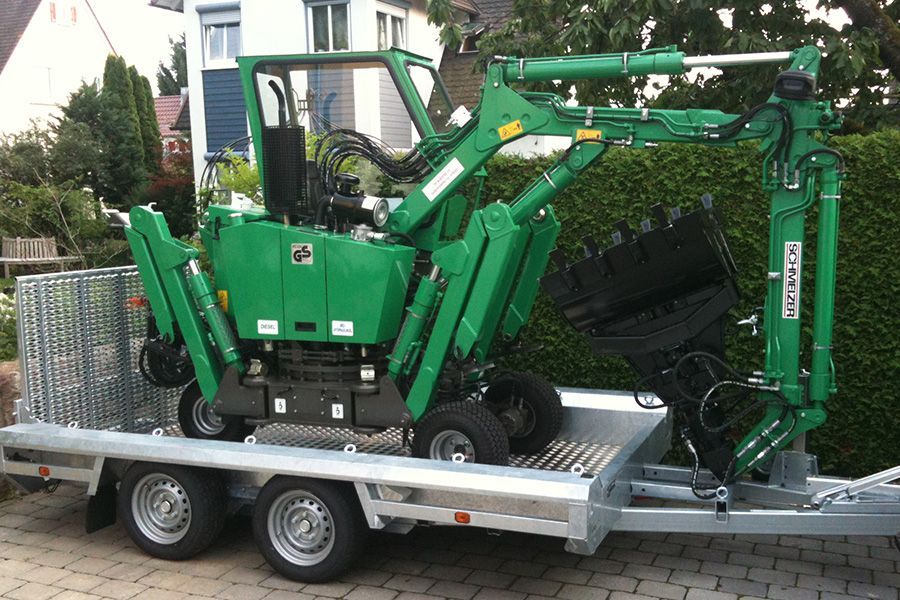 Mini-Bagger in grün auf Transporter