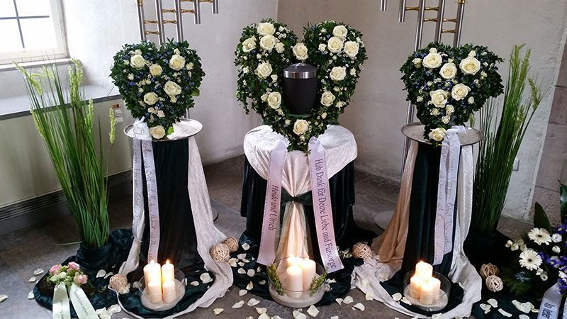 Blumenkränze in Herzform mit weißen Rosen auf geschmückten Säulen