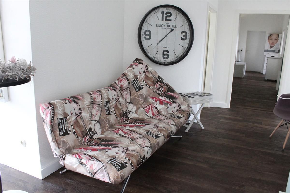 Eine Couch in einem Zimmer mit einer Uhr an der Wand