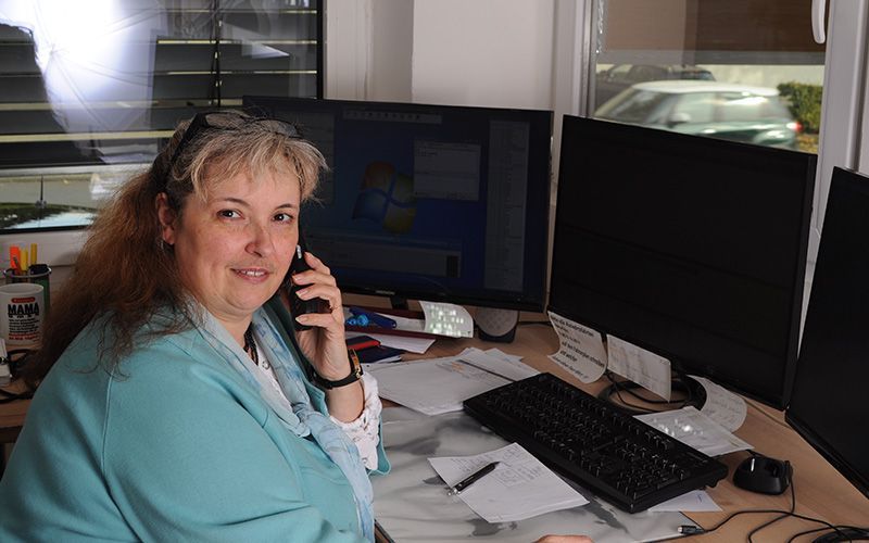 Eine Frau sitzt an einem Schreibtisch und telefoniert mit einem Mobiltelefon.