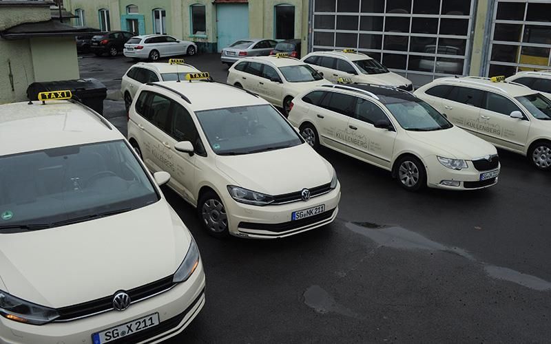 Eine Reihe weißer Taxis steht auf einem Parkplatz.