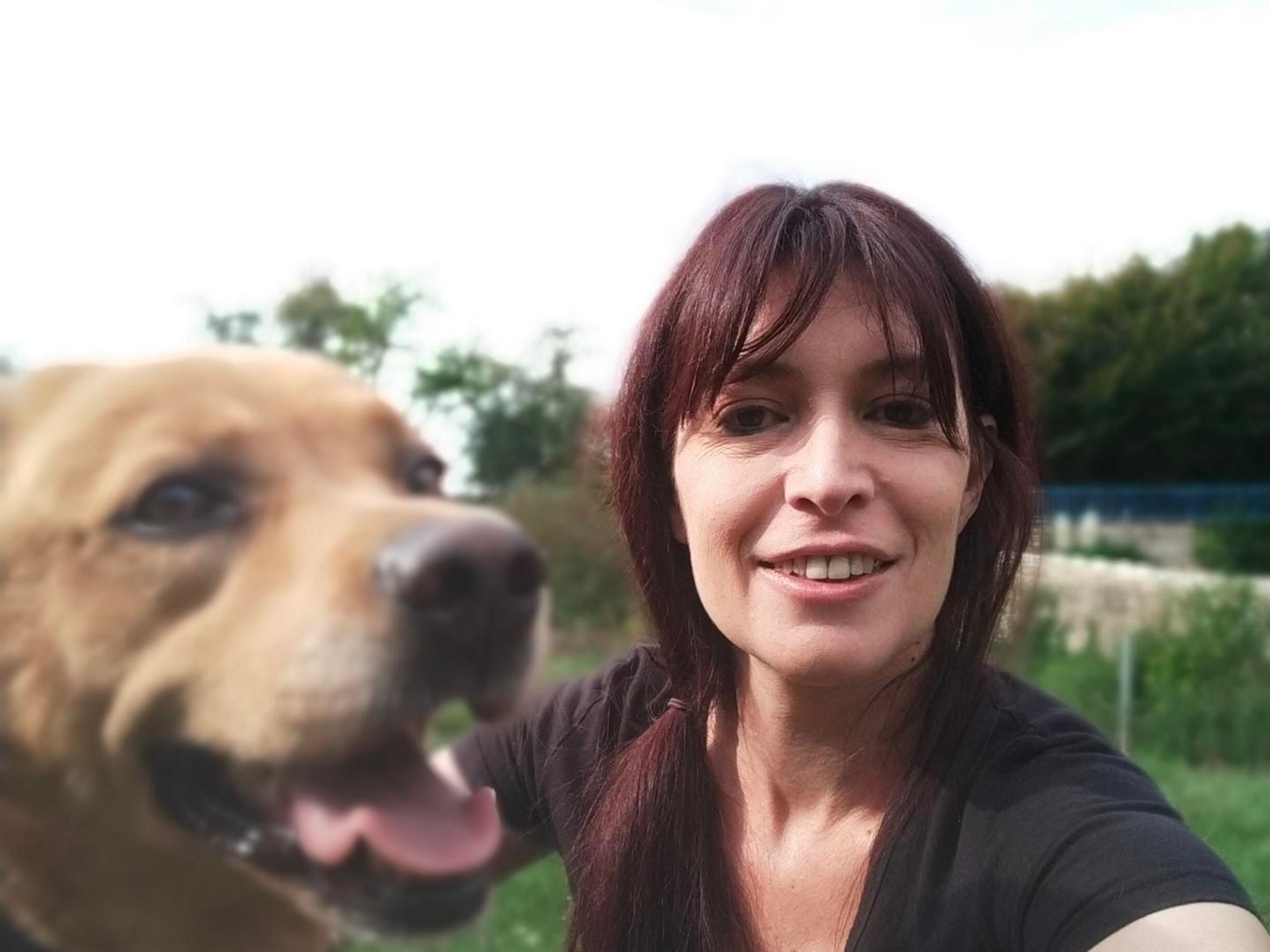 Julie Lepage à côté d'un chien brun clair à l'extérieur.