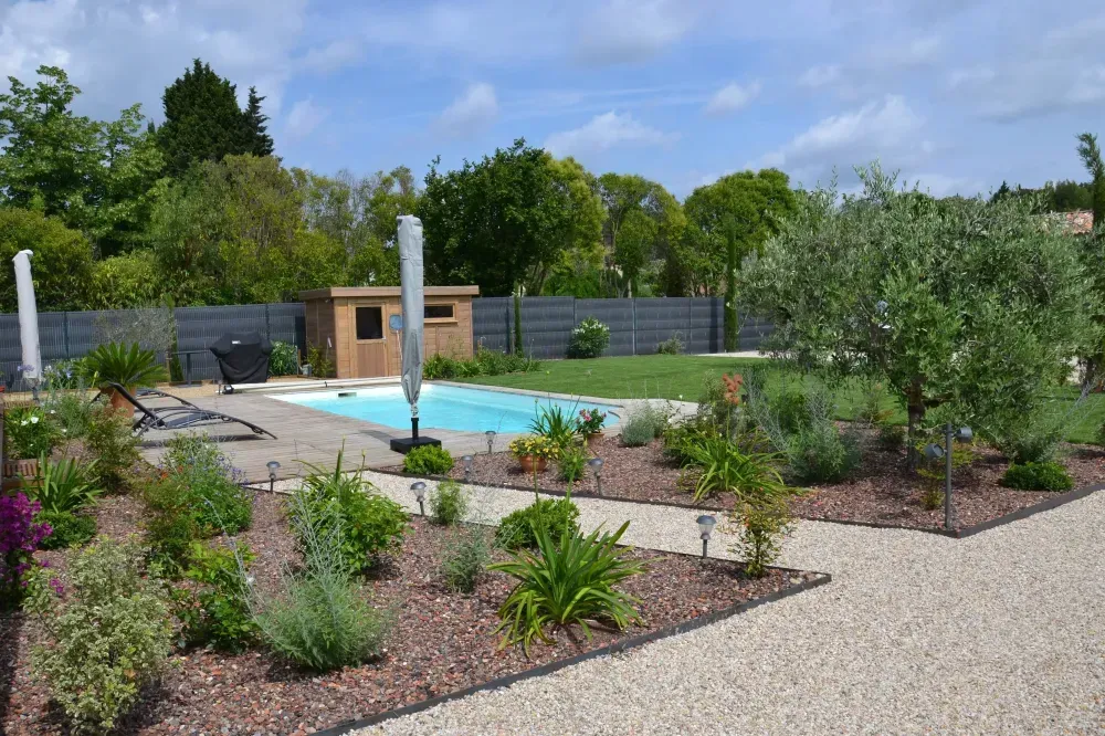 Jardin moderne avec piscine, allées en gravier et plantes désertiques aménagées sous un ciel bleu
