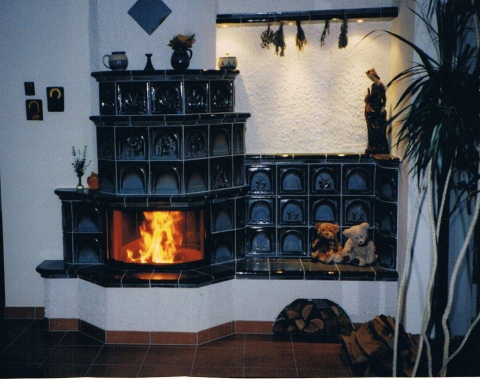 Kachelofen mit schwarzen Kacheln und sichtbarer Feuerstelle