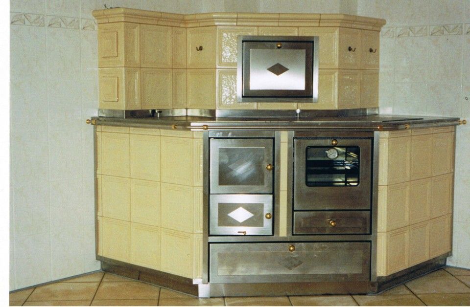 Kachelofen und Kochinseln in einem – Cremefarbene Kacheln und Edelstahlarbeitsfläche mit Herd und Ofen