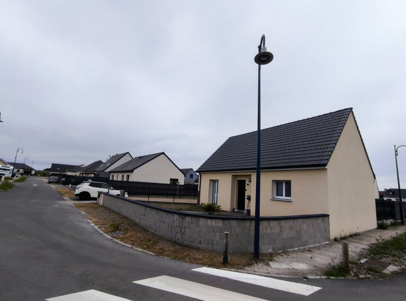 Des maisons à un coin de rue sous un ciel nuageux. Des maisons de plain-pied aux toits sombres.
