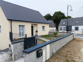 Maison beige au toit noir, petite cour derrière un muret, boîte aux lettres.