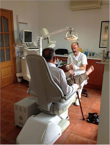Dentista examinando a un paciente en un sillón dental bajo una lámpara potente en una clínica