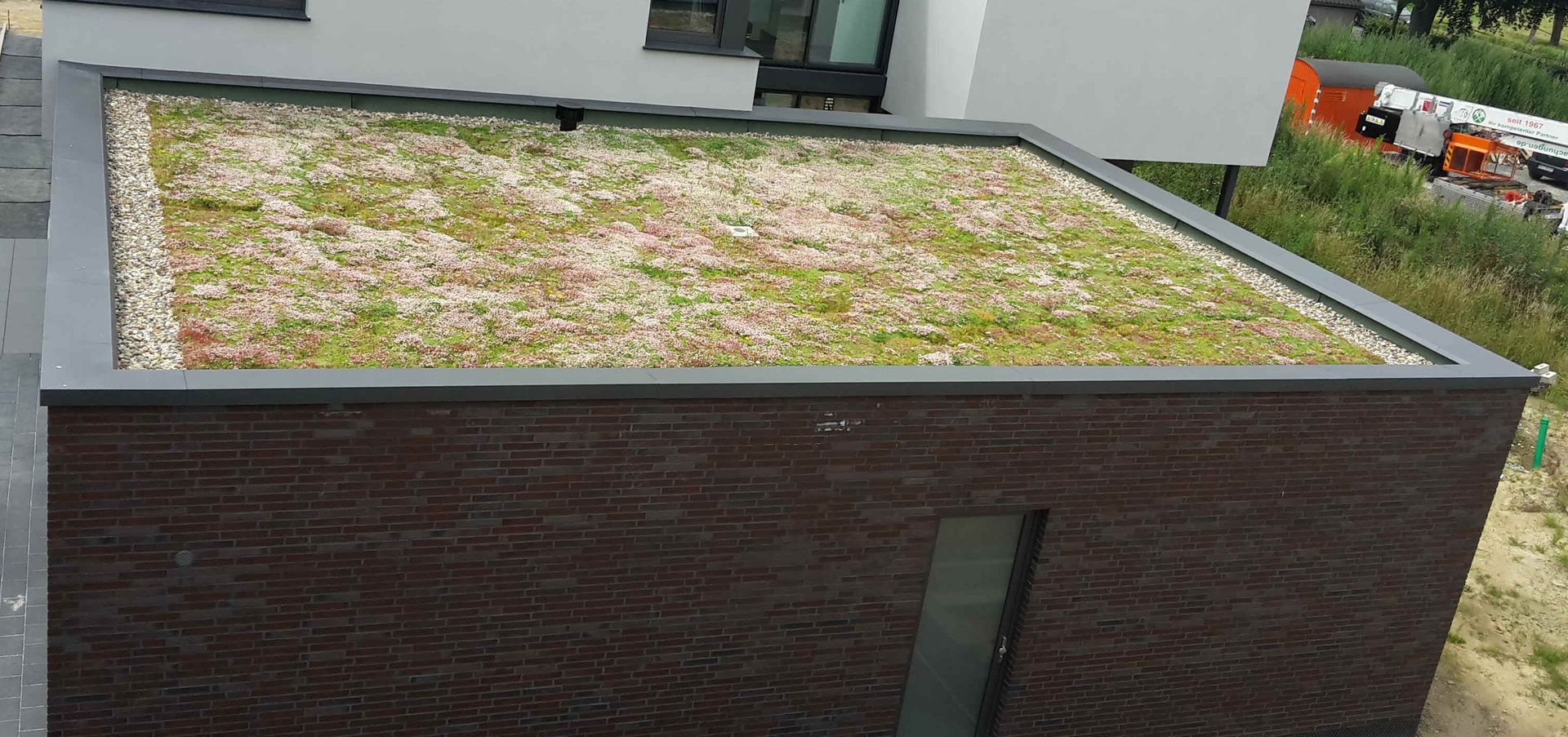 Modernes Haus mit Gründach um eine Terrasse herum