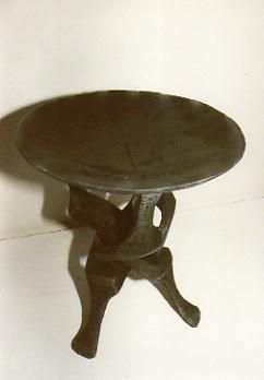 Ein Schwarzweißfoto eines kleinen runden Tisches mit drei Beinen.