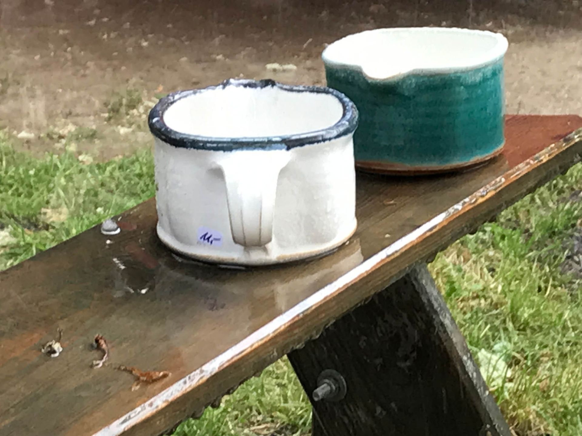 Zwei Keramiktassen stehen auf einer Holzbank.