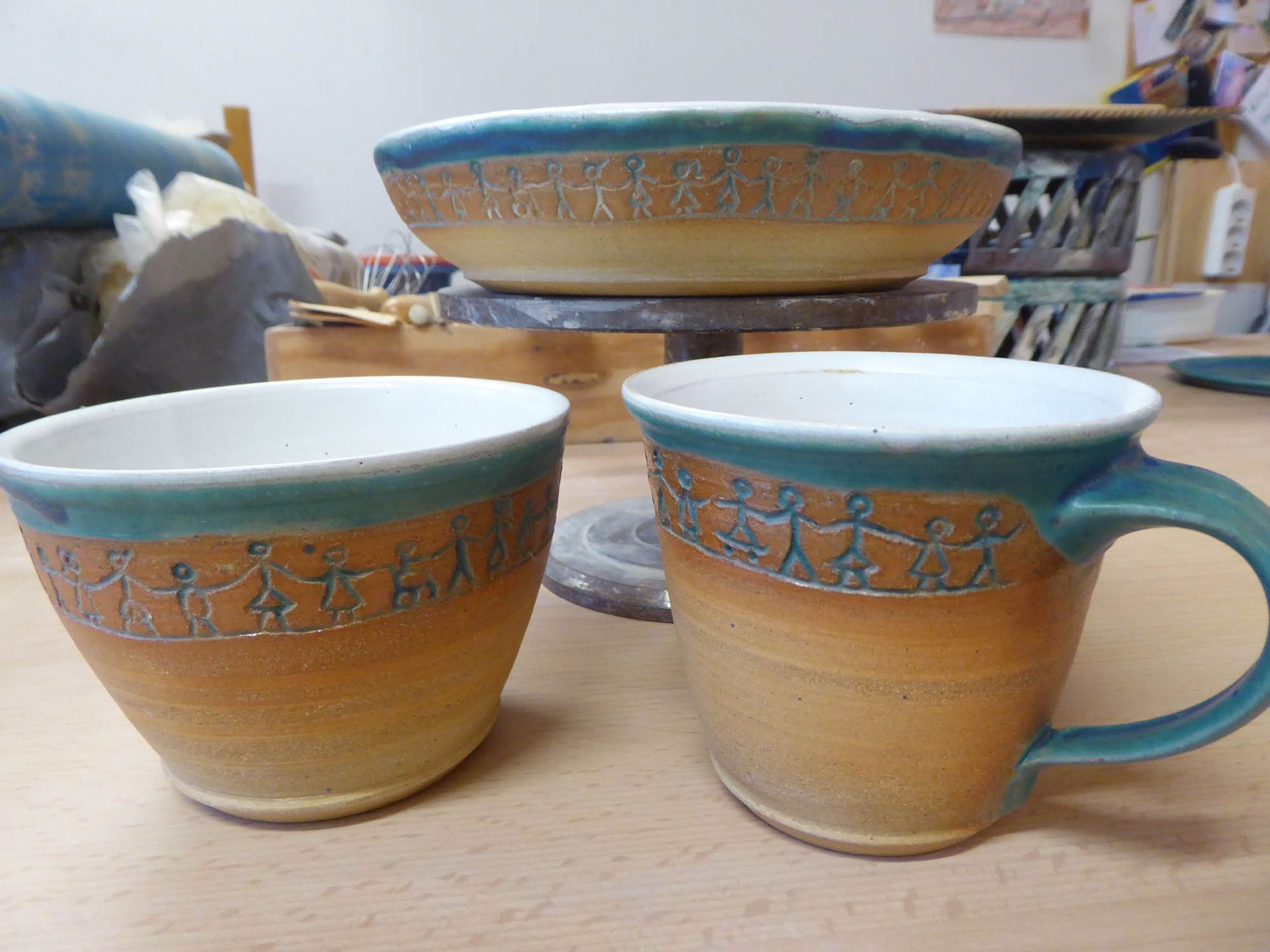 Zwei Tassen und eine Schüssel stehen auf einem Holztisch.