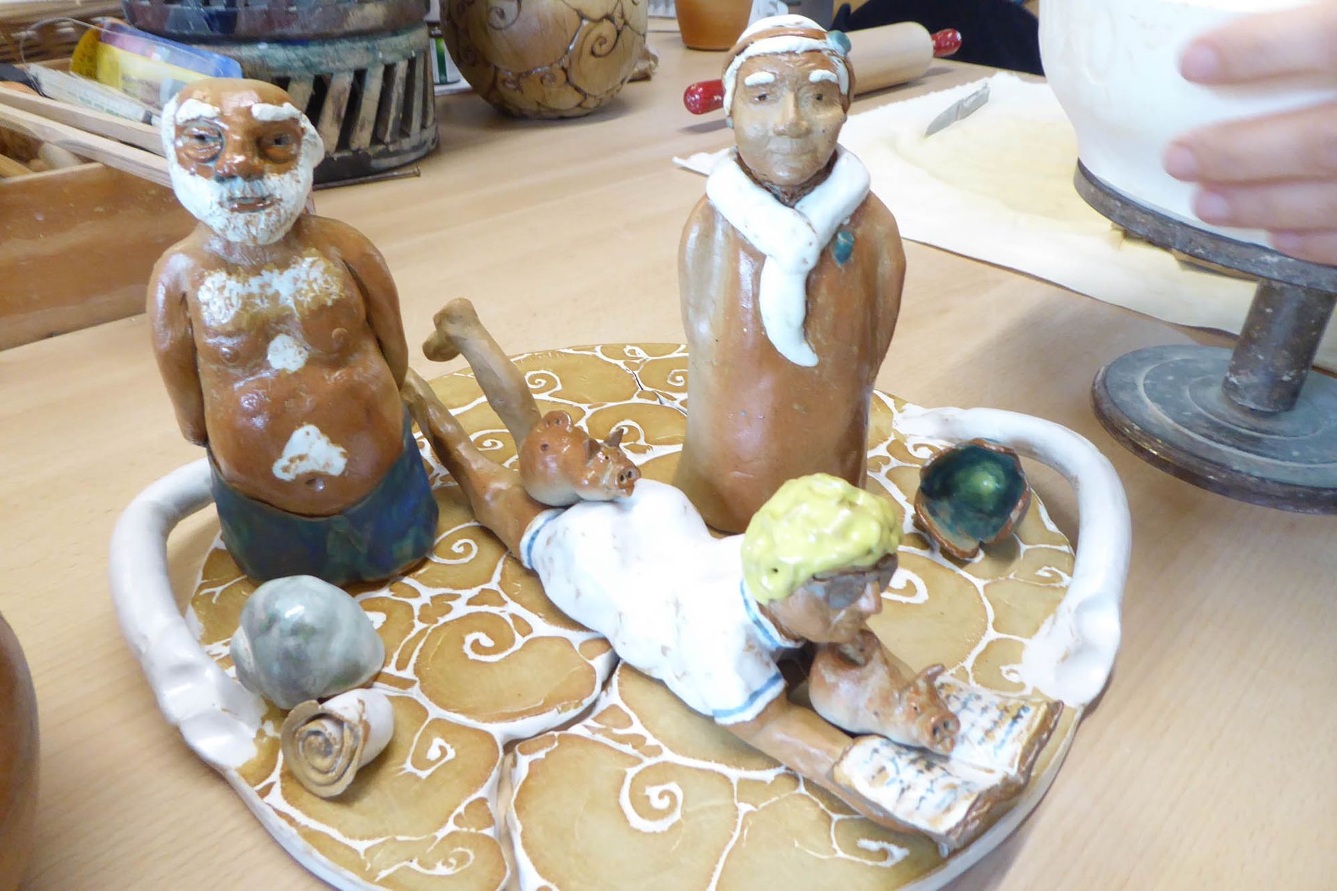 Eine Gruppe von Tonfiguren sitzt auf einem herzförmigen Teller