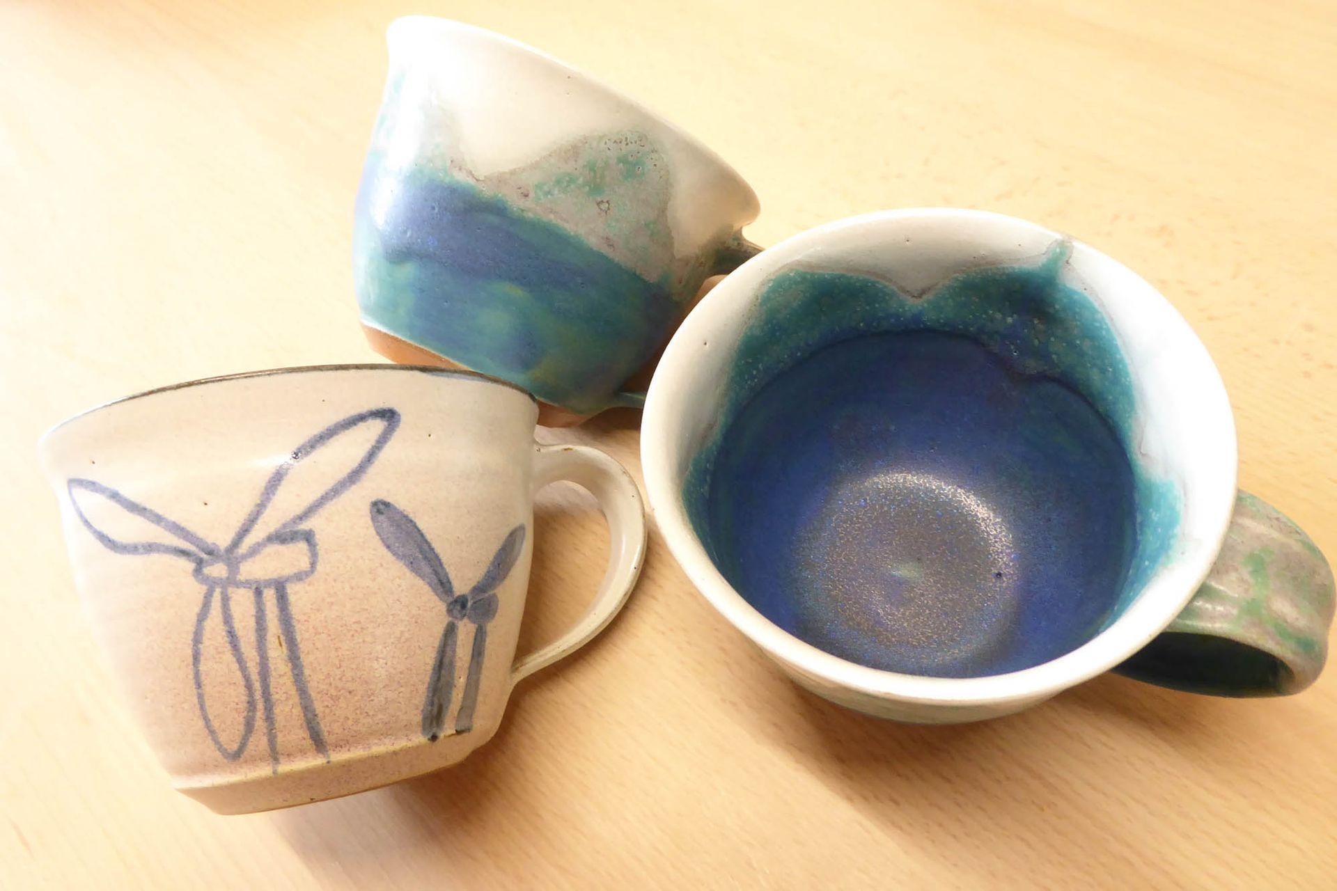 Drei Tassen stehen auf einem Tisch und eine davon hat eine Schleife darauf