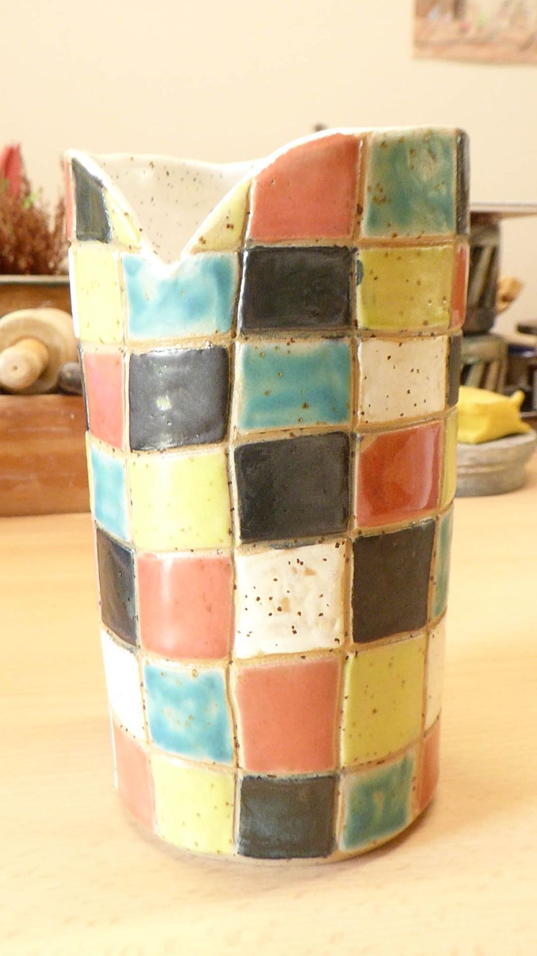 Auf einem Holztisch steht eine bunte Vase.