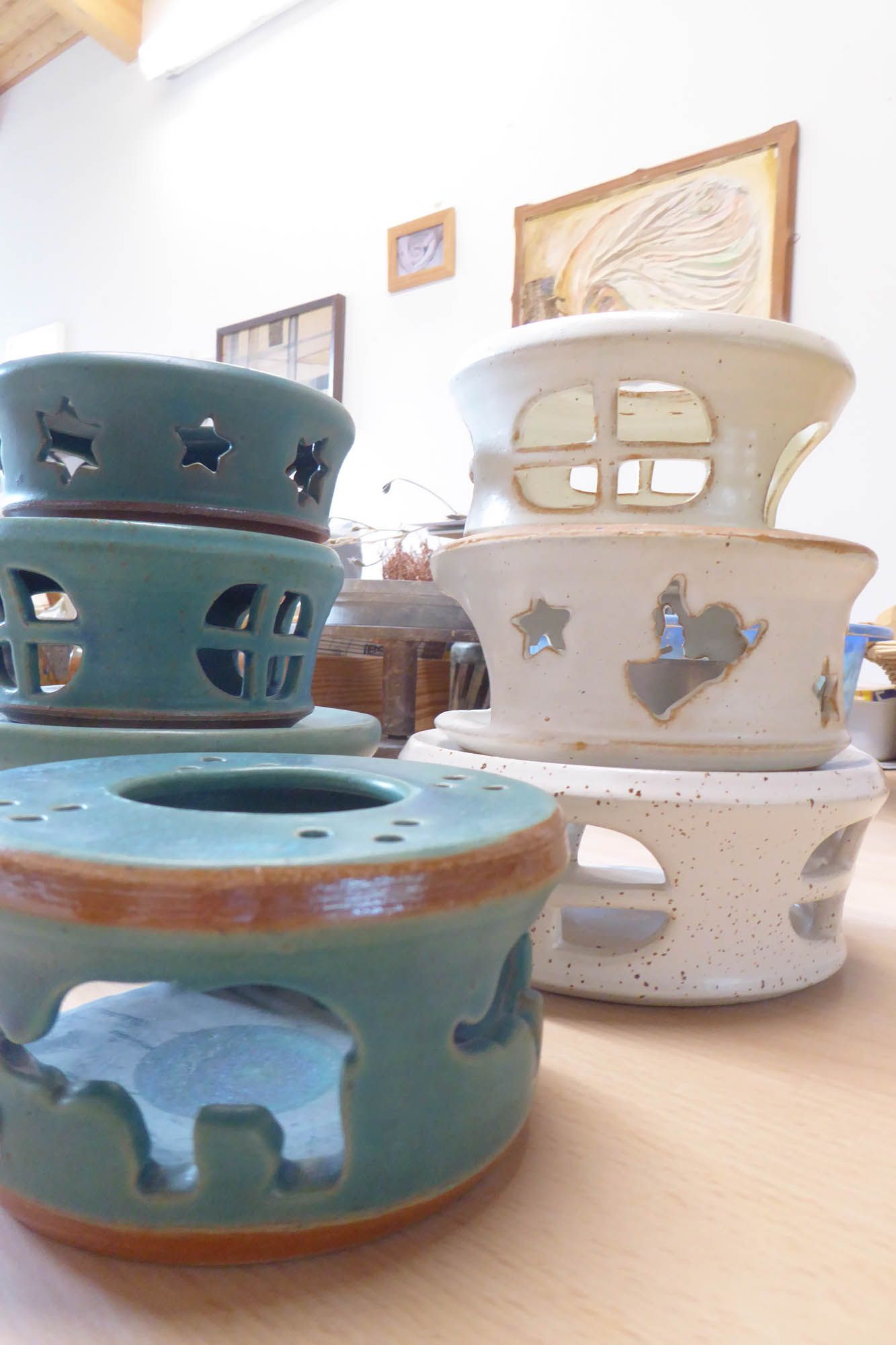 Eine Gruppe von Kerzenhaltern aus Keramik ist auf einem Tisch übereinander gestapelt.