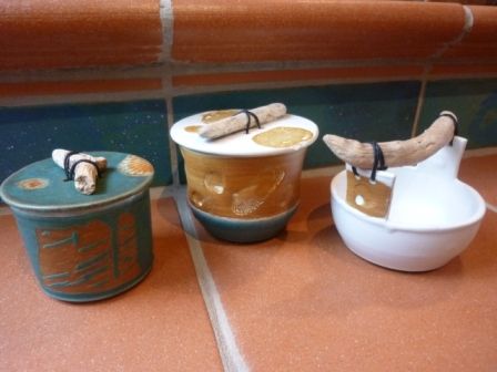 Drei Keramikbehälter mit Holzgriffen stehen auf einem gefliesten Boden