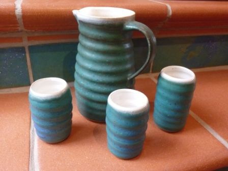 Ein Krug und drei Tassen stehen auf einer gefliesten Arbeitsplatte