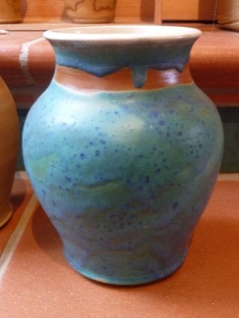 Eine blaue Vase steht auf einem Tisch neben anderen Vasen