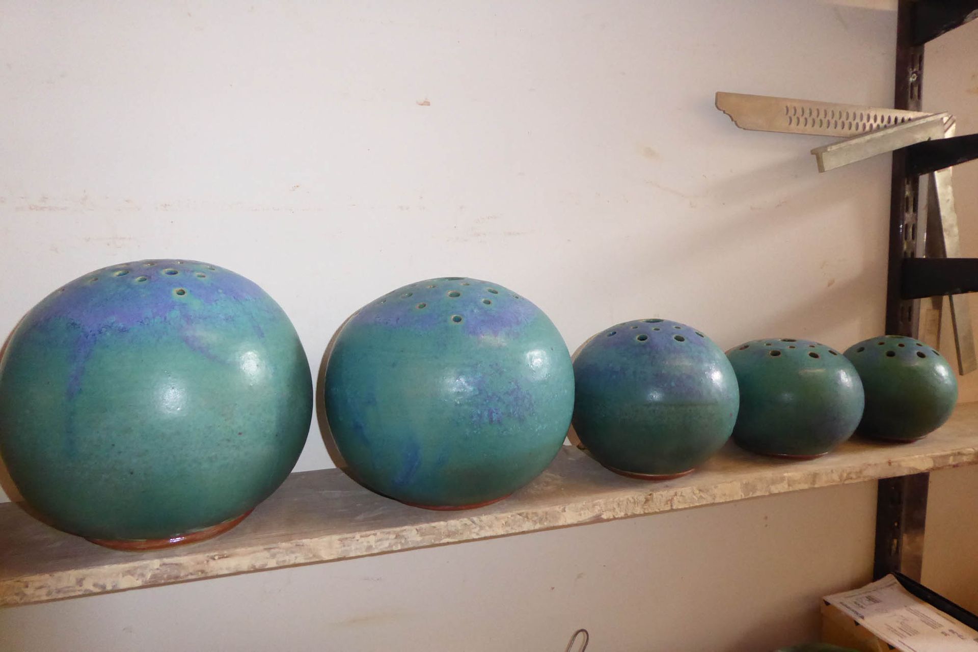 Eine Reihe grüner Bälle liegt auf einem Holzregal.