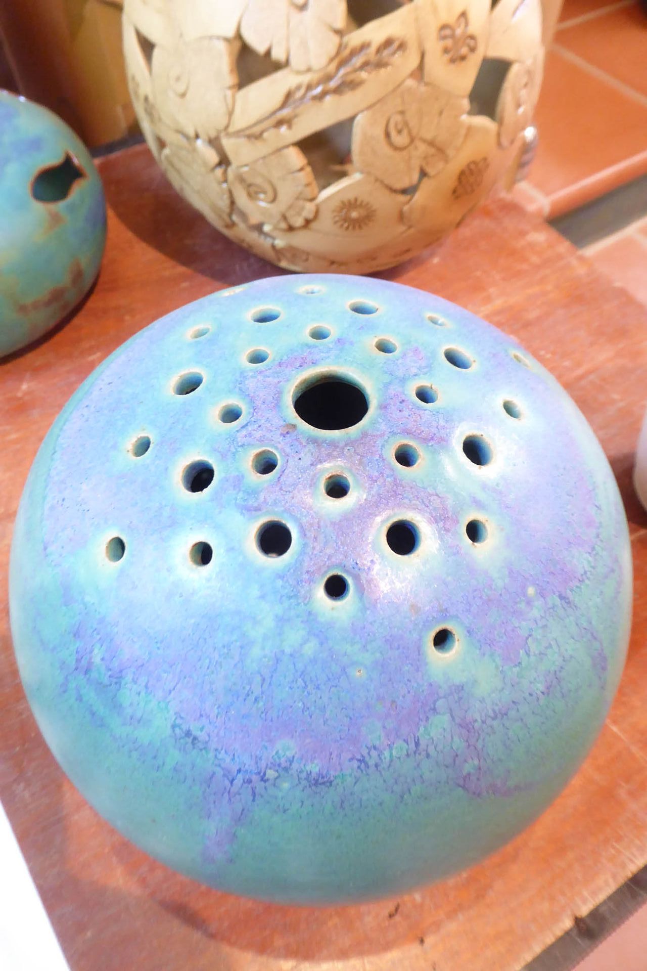 Auf einem Holztisch steht eine blaue Schüssel mit Löchern.