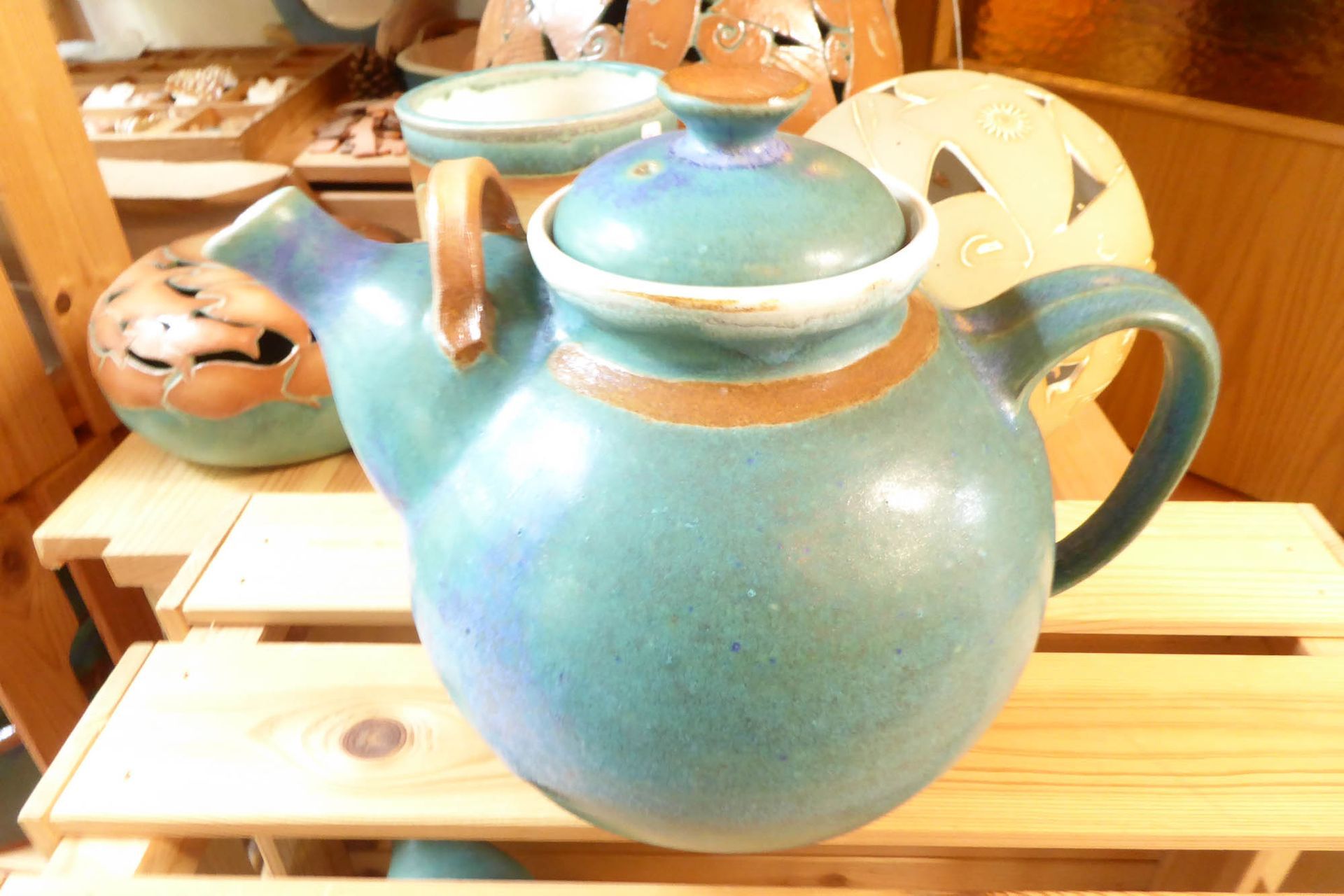 Eine blau-braune Teekanne steht auf einem Holzregal.