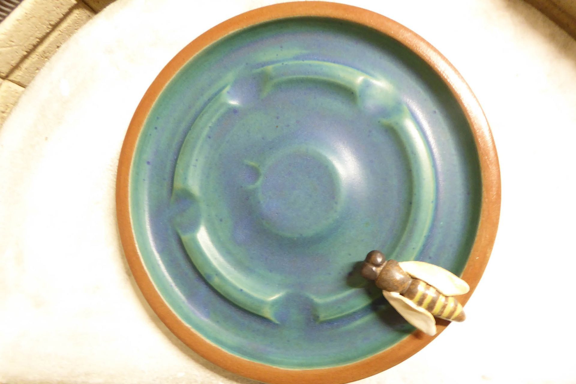Ein blau-brauner Teller mit einer Biene darauf