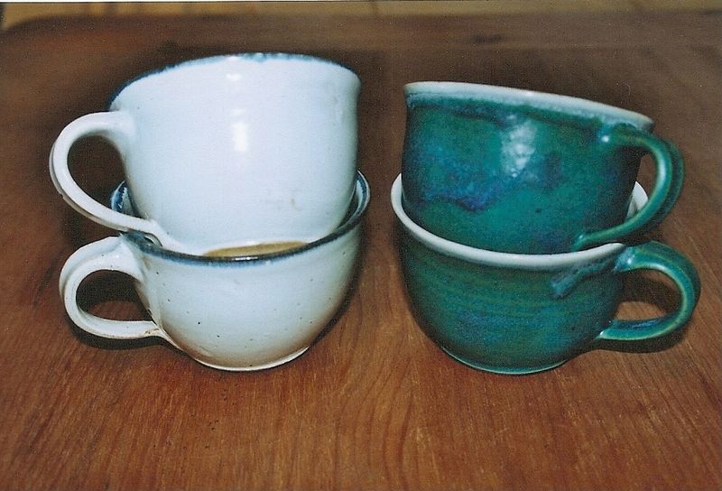 Vier Tassen sind übereinander auf einem Holztisch gestapelt