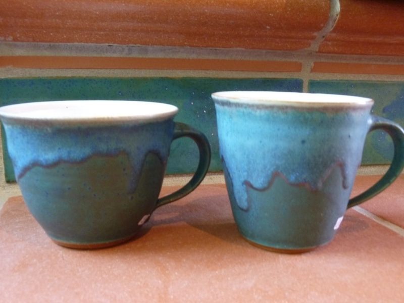 Zwei grüne Kaffeetassen stehen auf einem Tisch